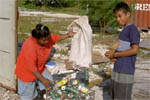 woman and a boy dumping recyclables into a crate outside