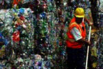 worker in a vest and helmet in front of bales of plastic